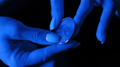 Woman's Hands Hold Bitcoin Under Blue Light