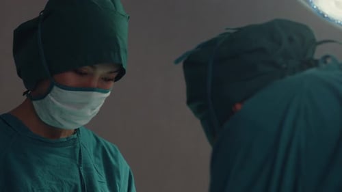 assistants and nurses performing invasive surgery on patient in hospital operating room.