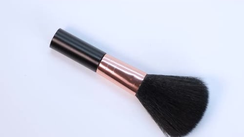 Small makeup brush detail shot, rotating motion on white surface background. Close up view of makeup