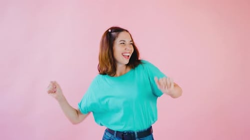 Happy Young Woman Dancing on Pink Background