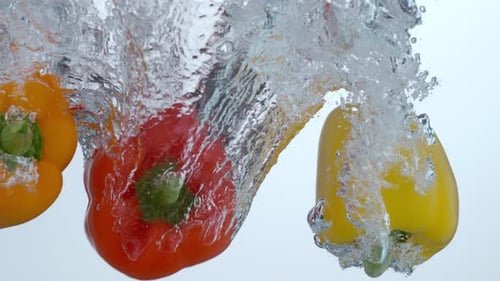 Colorful Bell Peppers Splash Down Into Refreshing Water