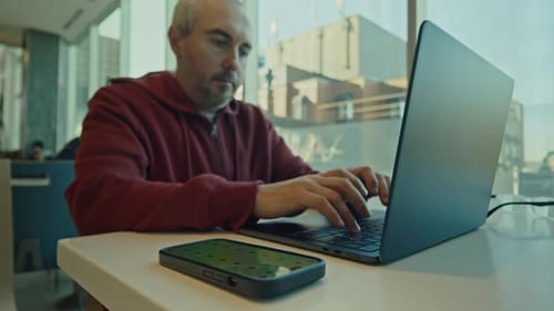 Homem com visão lateral usando smartphone e laptop para compras on-line com cartão de crédito