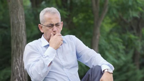 Man coughing outdoors, lung problem.