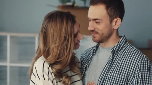 Loving Couple Smiles and Kisses on Forehead Indoors