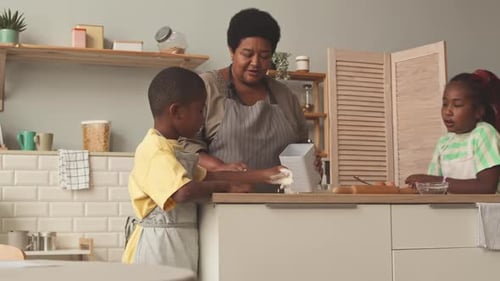 Woman Baking with Children in a Bright Kitchen