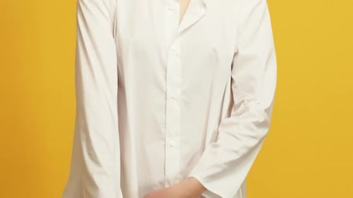 Woman Buttons White Shirt on Yellow Background