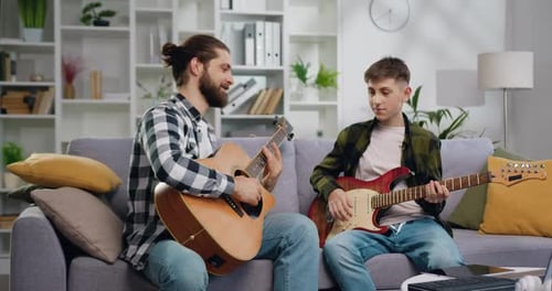 Father and Son Playing Guitars Together at Home