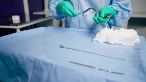 Closeup in Operating Room the Lower Surgeon in Green Gloves Lays Out Instruments on the Surgical
