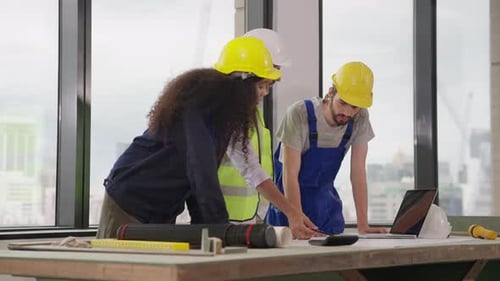 Engenheiros usando o plano de projeto, discutindo e trabalhando