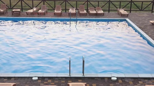 Blick von oben auf den Swimmingpool mit klarem Wasser im Urlaub vor dem Hintergrund des Sonnenuntergangs