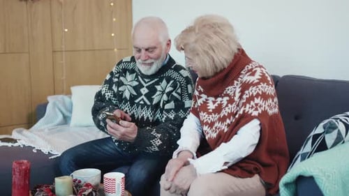Senior Couple Using Phone Together Indoors at Christmas