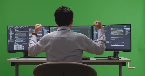 Developer Celebrating While Write Code With Multiple Computer Screens In Green Screen Studio