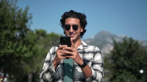 Happy Latino Man Use Smartphone Chatting Online Message at Summer Mountain Urban Park Panorama Shot