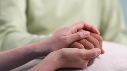 Asiatische Pflegekraft, die Händchen hält ältere ältere Männer, kümmert sich im Pflegeheim um die psychische Gesundheitsversorgung.