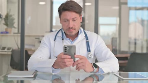 Mature Adult Doctor Using Smartphone in Clinic