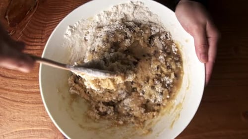 Video von oben nach unten, in dem Schokoladenkeksteig in einer Schüssel auf dem Tisch gemischt wird