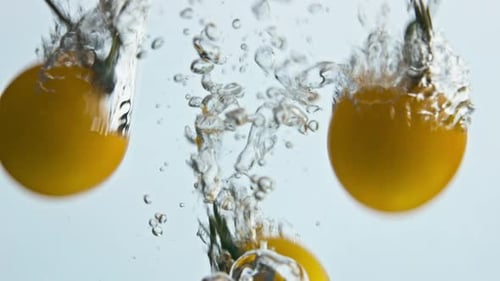 Yellow Tomatoes Plunging Into Water With Bubbles