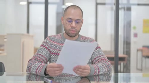 Man Reviews Documents at Office Desk