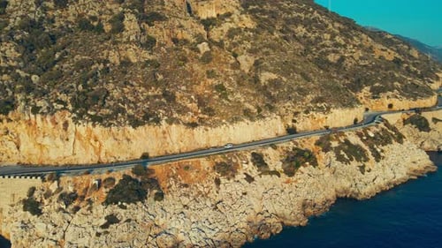 Aerial Car Move Overhead Winding Road Along the Coastline at Sunset