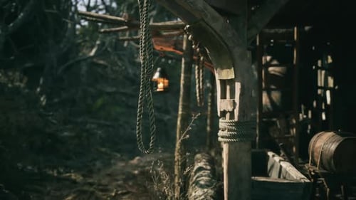 Rustic Wooden Structure with Hanging Lantern and Ropes in Natural Setting
