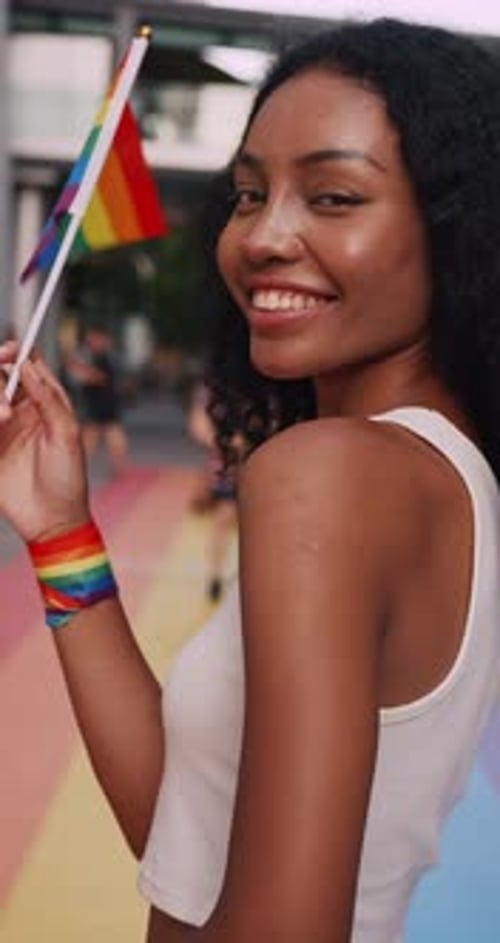 Vertical clip. A young black woman shows off her homosexual identity in a pride parade.