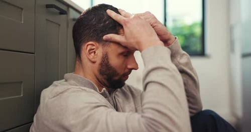 Stressed Man with Head in Hands Sits Indoors
