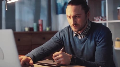 Un professionnel concentré et dévoué travaillant sur un ordinateur portable dans un espace de bureau à domicile moderne