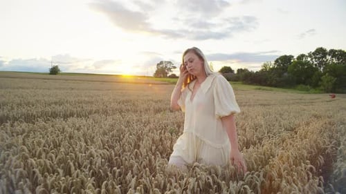 A Romantic Woman Walks in a Wheat Field at Sunset