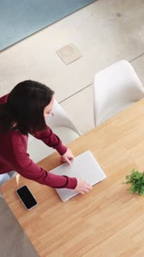 Mulher abrindo laptop e começando a trabalhar em casa