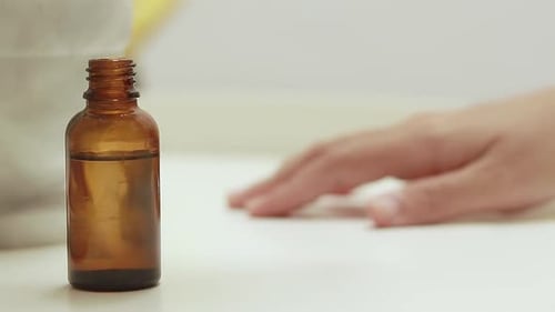 Woman Applies Serum from Amber Bottle to Hand