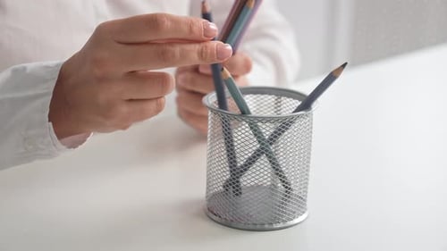 Hands Organizing Pencils in Wire Mesh Holder