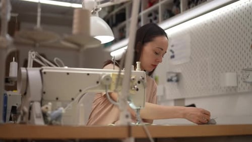 Young Tailor Female Sewing Fabric on Sewing Machine in Workshop Focused on Creating Highquality