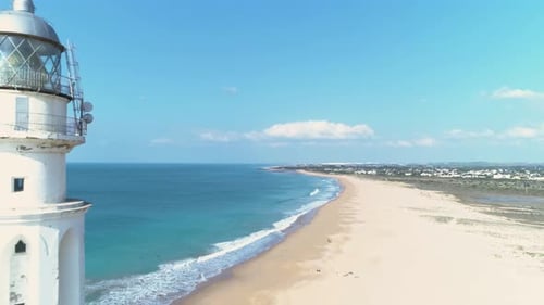 Aerial reveal view of the Trafalgar lighthouse on the beach Los Canos de Meca