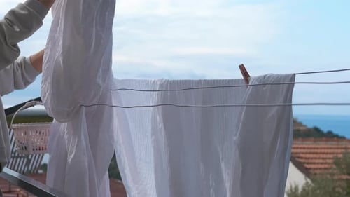 Woman Hangs Laundry on Clothesline in Coastal Town