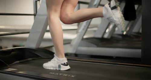 A Young Beautiful Brunette Girl in Sportswear Exercises on a Simulator in the Gym Doing Cardio