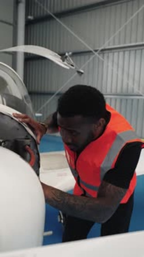 Aircraft Maintenance Engineer Inspecting Airplane Engine in Hangar