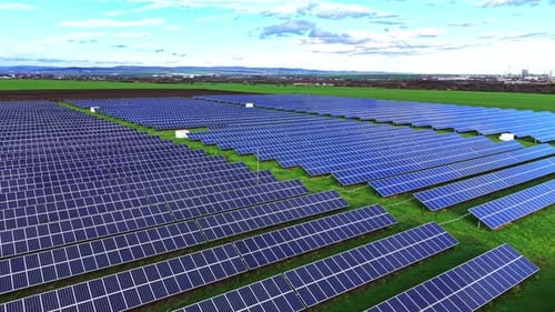 Vast solar panel array in a green field under clear blue skies