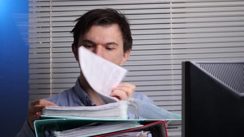 Young Man Reviewing Files and Documents at Office