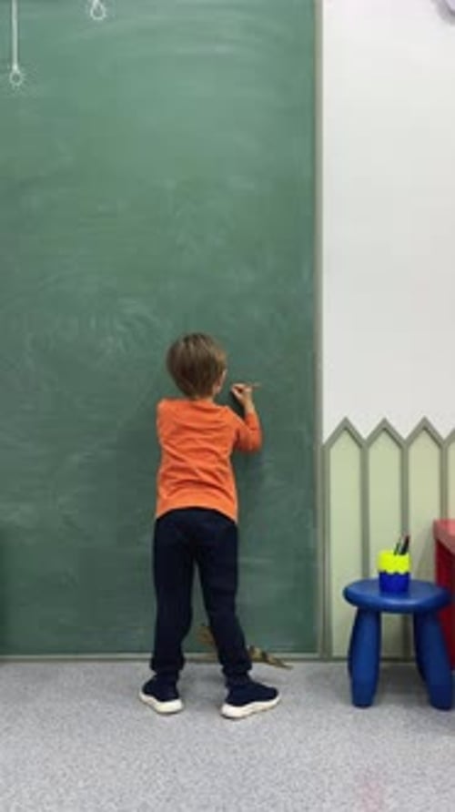 Adorable Toddler Little Boy Drawing Writing on Blackboard or Chalkboard at Kindergarten