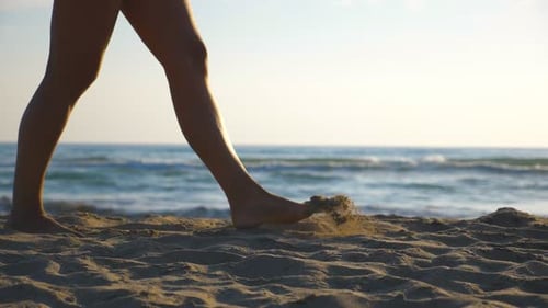 Close Up of Female Feet Walking at the Beach with Tranquil Sea Waves at Background Legs of Young