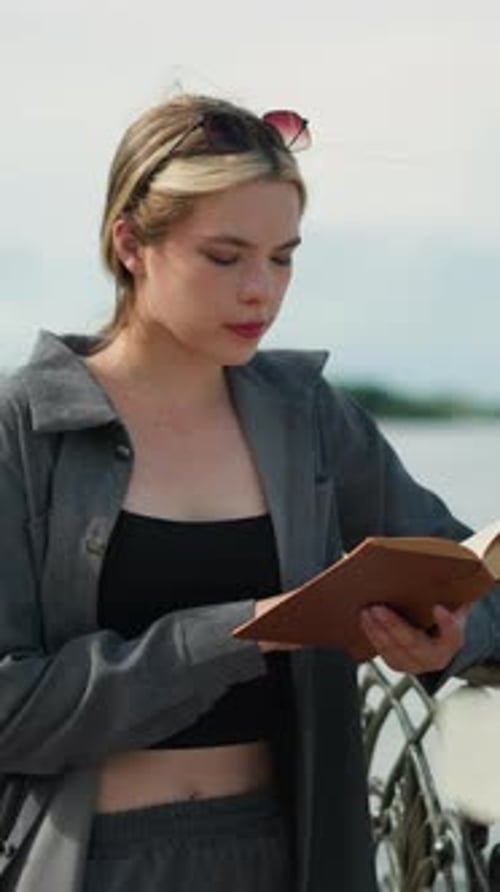 Woman Reading Book Outdoors by a Stone Ledge