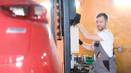 A Professional Car Mechanic Examines a Car at a Car Service Performing a Series of Tests