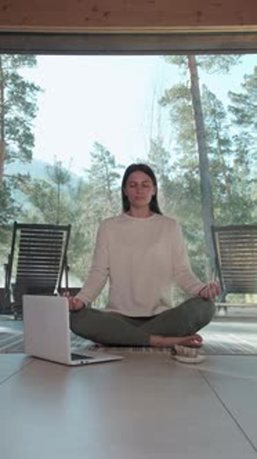 Woman Practicing Online Yoga in Front of Laptop at Home
