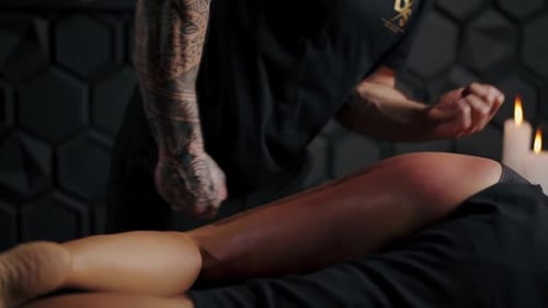 Man Massaging Woman's Leg with Candles in Background