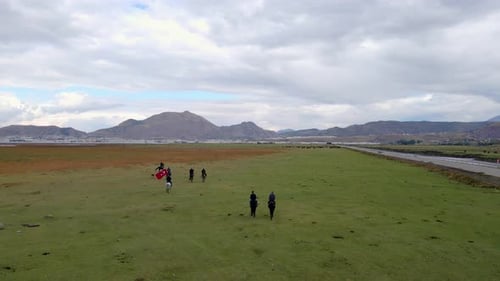 People Riding Horses Across Green Rural Field