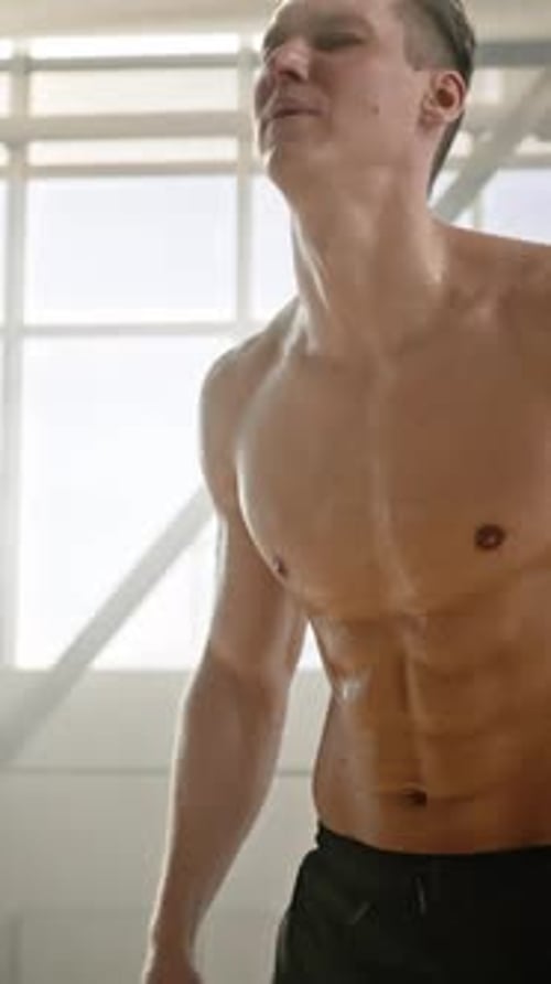 Confident Male Athlete Wiping Off Sweat When Exhausted Resting After Intense Workout in Smokey Gym