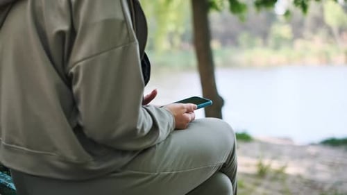 Woman Using Phone By Lake in Park
