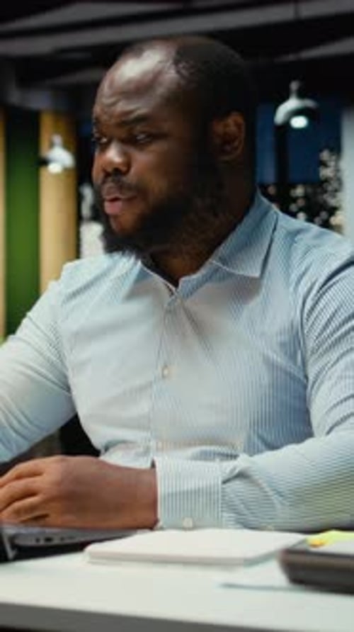 Vertical Video Black Businessman Engaging in Online Video Call From Dark Office