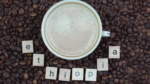 Top View of a Cup of Coffee on a Background of Coffee Beans with the Inscription Ethiopia