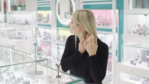 Girl admires sparkling jewelry in slow motion at a store mirror while selecting a special gift